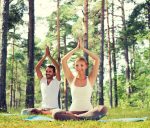 sport, fitness, yoga and people concept - smiling couple meditat